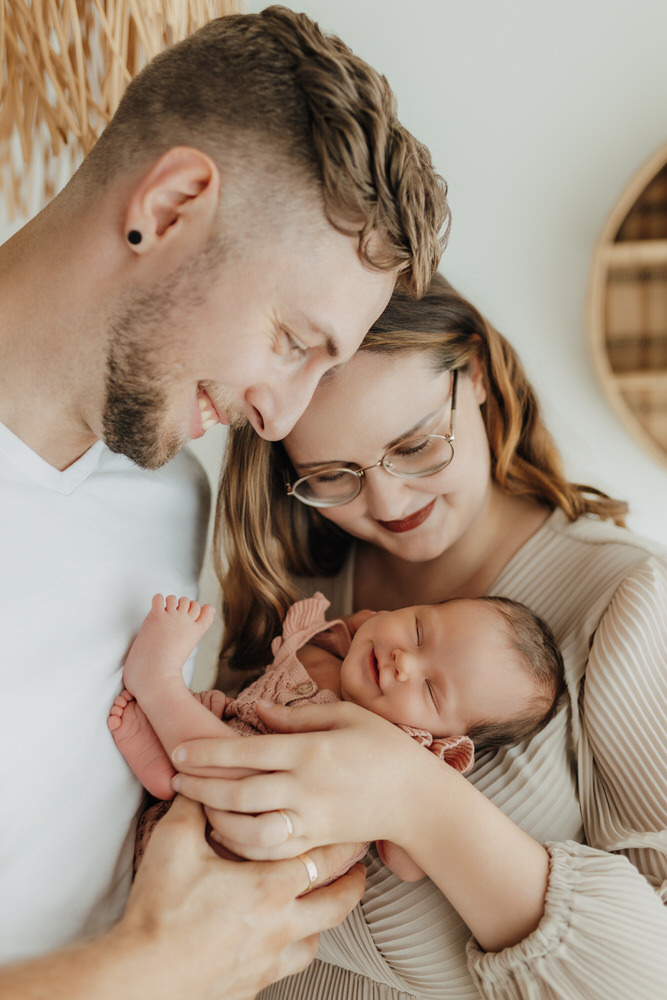 Paar mit Baby auf Arm bei Neugeborenenshooting im Studio