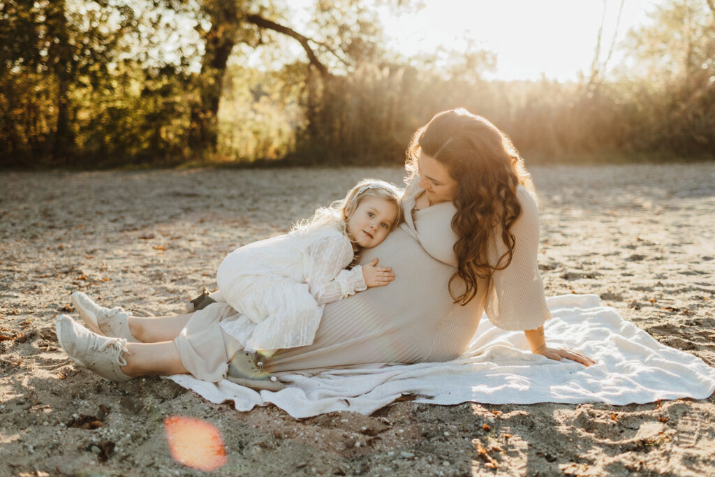 Frau mit Kind auf Decke liegend bei Babybauchshooting am See